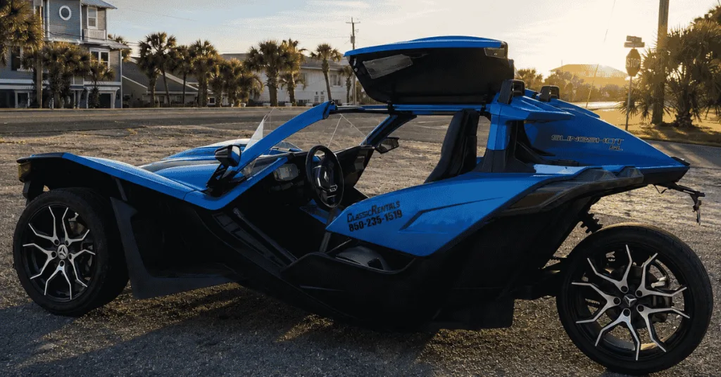 Blue Polaris Slingshot rental parked by palm trees and beach homes in Panama City Beach, ready for Thunder Beach